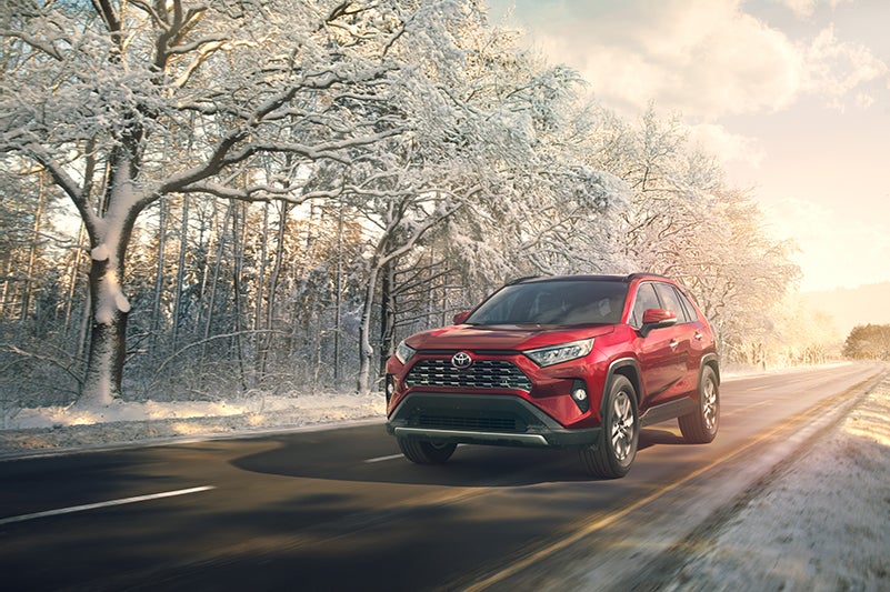 A Hybrid for Everyone at Fiore Toyota | Red toyota RAV4 running on road in winter